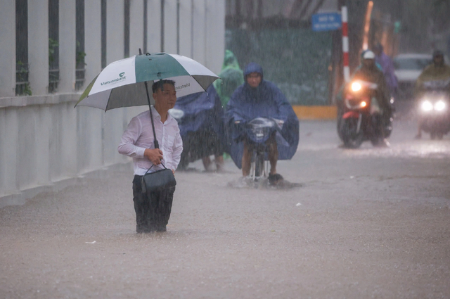 Người dân Hà Nội chật vật 'đắp đập' ngăn nước, bơi thuyền trên phố - Ảnh 2.