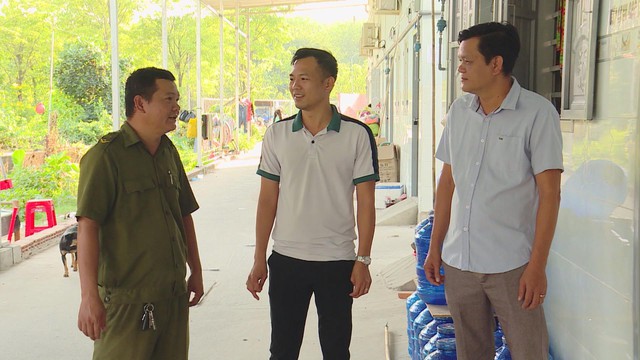 Cán bộ an ninh mặc đồng phục đang đứng nói chuyện cùng hai người đàn ông tại hành lang khu nhà trọ công nhân - Ảnh 1.