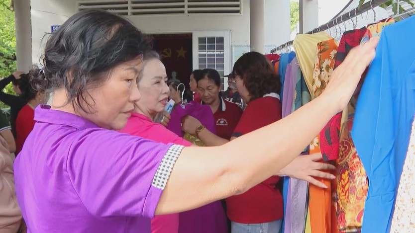 Các chị em phụ nữ và hội viên tập trung bên sào đồ di động, tay nâng lên tìm kiếm và ướm thử những bộ áo dài nhiều màu sắc - Ảnh 5.
