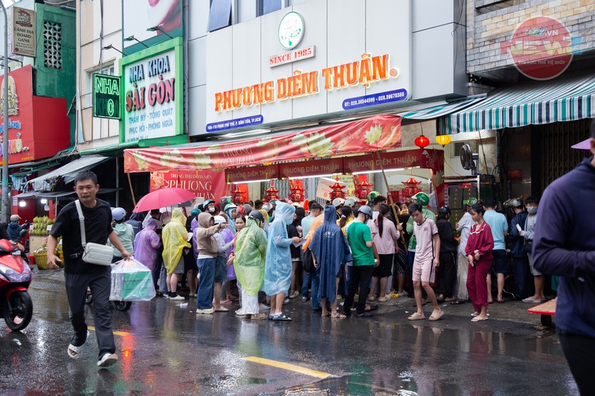 Tiệm tăng giá bánh trung thu, khách vẫn đội mưa chờ đến lượt - Ảnh 1.